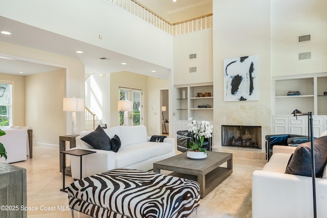 living room with light tile patterned flooring, built in shelves, visible vents, and a premium fireplace