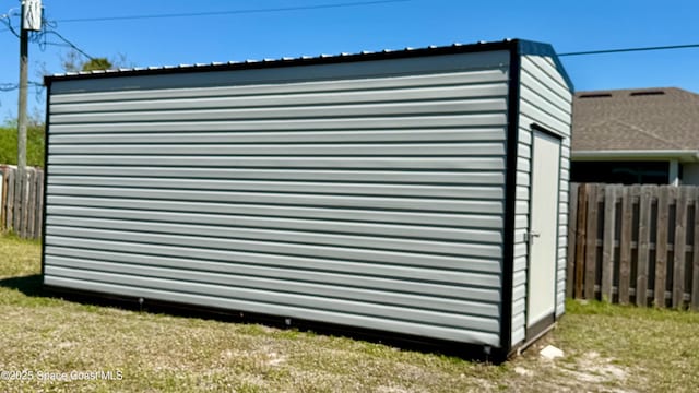 view of outdoor structure with fence and an outbuilding