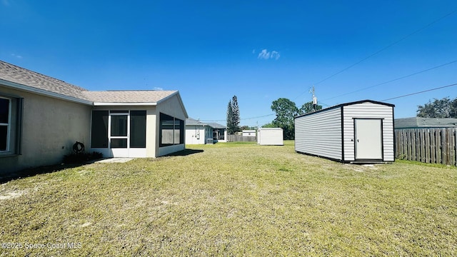 view of yard featuring an outbuilding, a storage unit, fence, and a sunroom