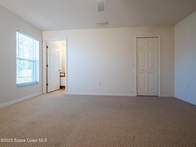 unfurnished room featuring a textured ceiling, baseboards, and light colored carpet