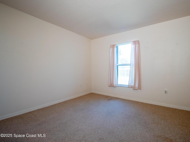 spare room featuring light carpet, a textured ceiling, and baseboards