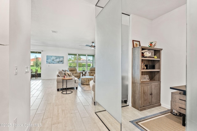 hall with visible vents, wood finish floors, and a wealth of natural light