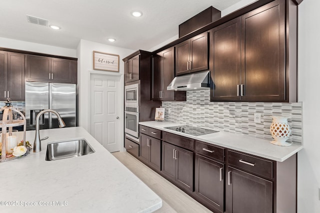 kitchen featuring visible vents, stainless steel appliances, dark brown cabinets, under cabinet range hood, and a sink