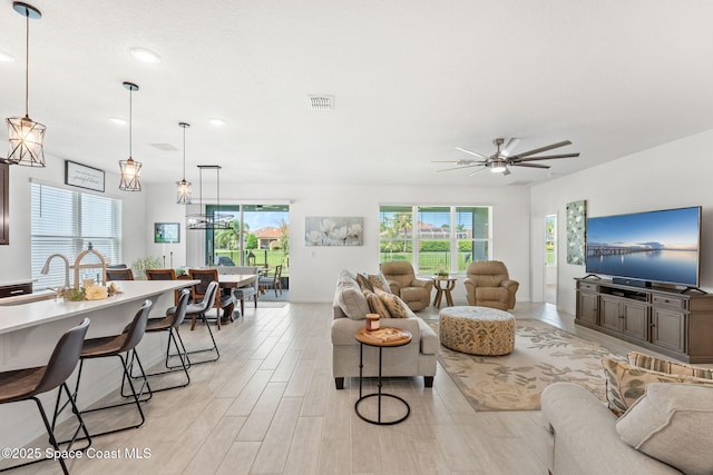 living area featuring a ceiling fan, visible vents, and light wood finished floors