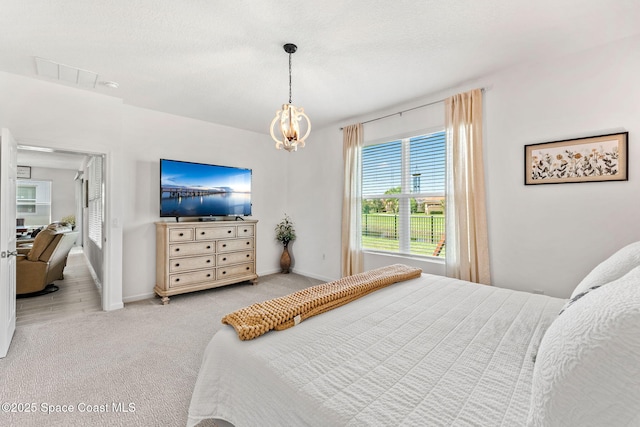 carpeted bedroom featuring an inviting chandelier, baseboards, and a textured ceiling