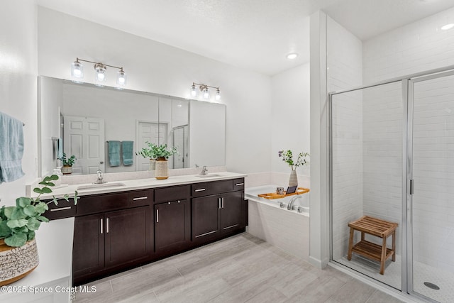 bathroom featuring a bath, a shower stall, double vanity, and a sink