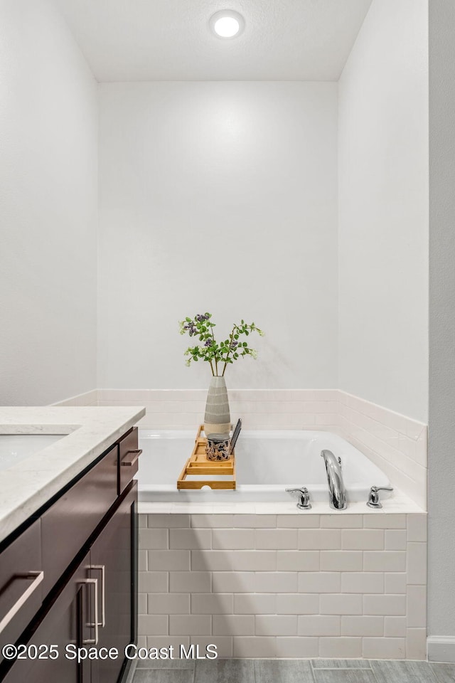 full bathroom featuring a bath and vanity