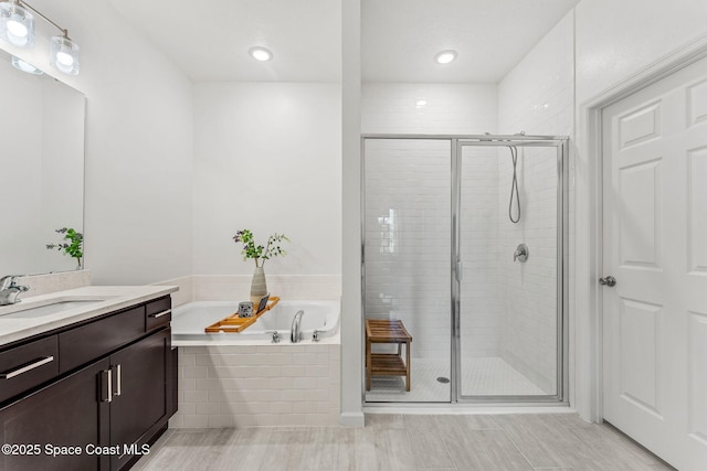 full bathroom with a stall shower, a bath, and vanity