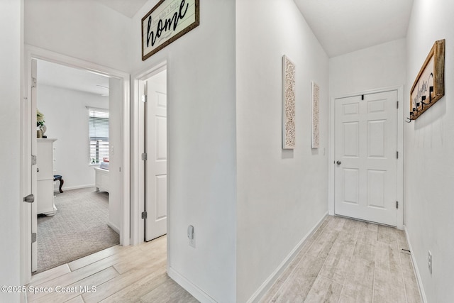 corridor with light wood-style flooring and baseboards