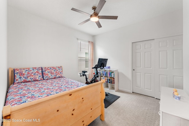 bedroom featuring light carpet, ceiling fan, baseboards, and a closet