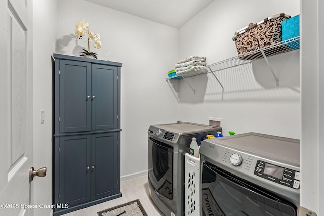 laundry room with washing machine and dryer, cabinet space, and baseboards