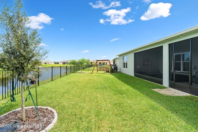 view of yard featuring a playground, a fenced backyard, a sunroom, and a water view