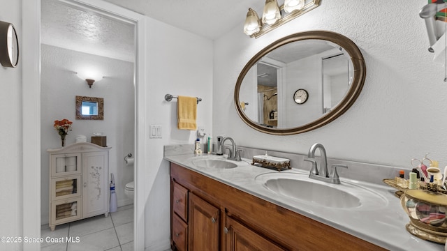 full bathroom featuring double vanity, tile patterned flooring, a sink, and toilet