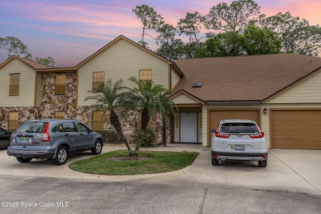 view of front of house featuring a garage, stone siding, roof with shingles, and concrete driveway