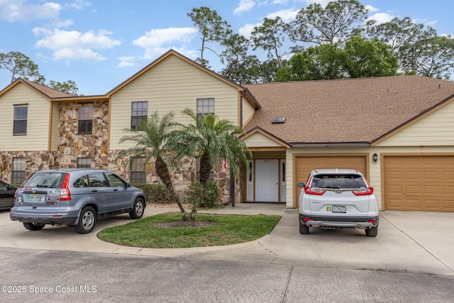 multi unit property featuring a garage, concrete driveway, a shingled roof, and stone siding