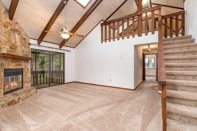 unfurnished living room featuring a stone fireplace, stairway, carpet, and wooden ceiling