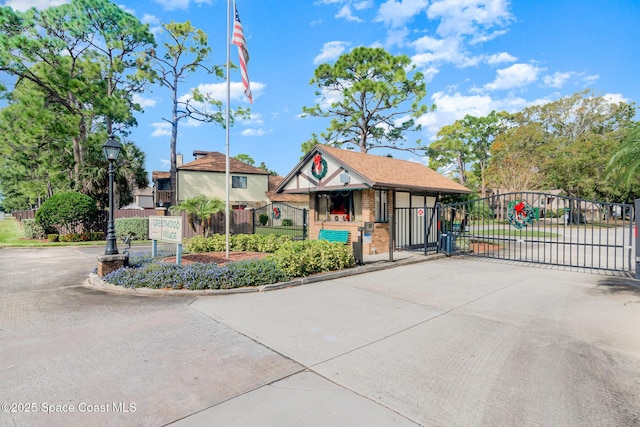 tudor house featuring driveway, a gate, fence, and brick siding