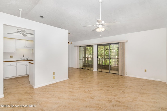 empty room featuring visible vents, a sink, baseboards, and ceiling fan