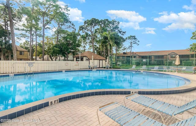 pool with a patio area and fence