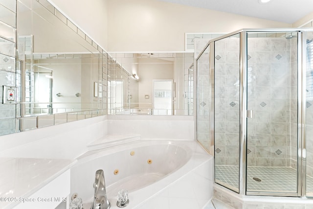 bathroom featuring a stall shower, a tub with jets, and vaulted ceiling