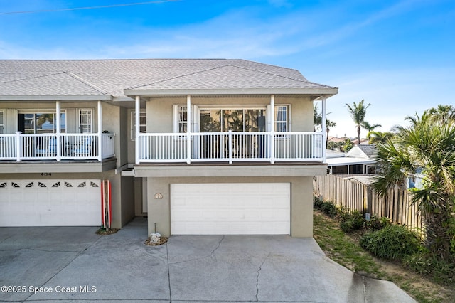 view of front of house with an attached garage, a shingled roof, fence, driveway, and stucco siding