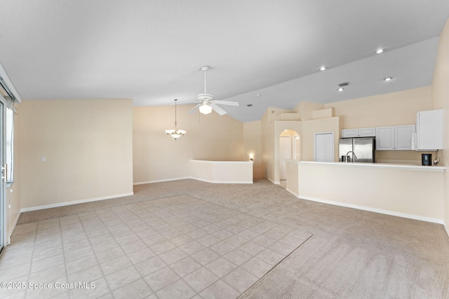 unfurnished living room with lofted ceiling, light carpet, baseboards, and ceiling fan with notable chandelier