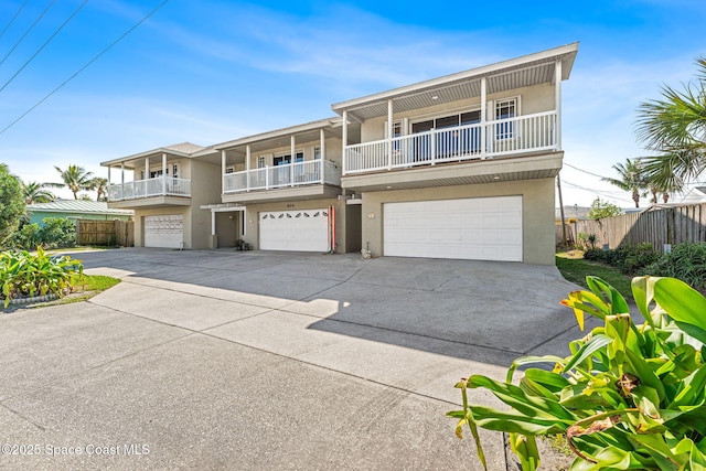 view of front of house featuring a garage, driveway, fence, and stucco siding