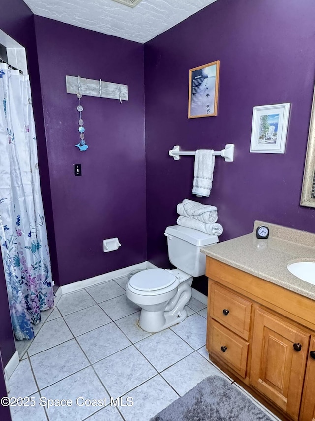 bathroom with toilet, a textured ceiling, vanity, tile patterned flooring, and baseboards