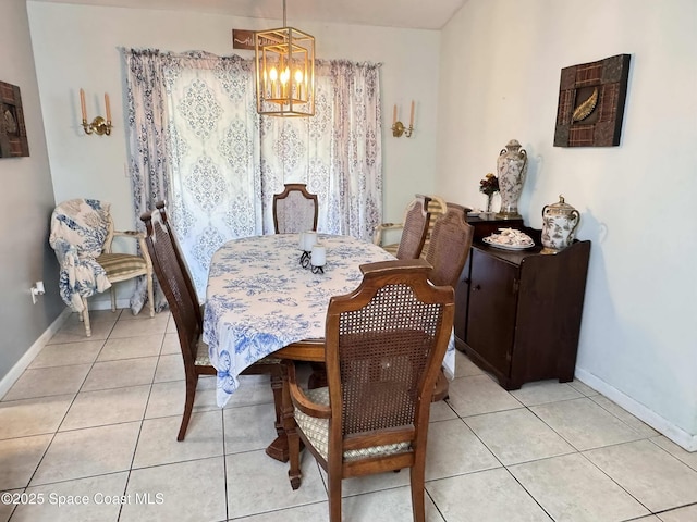 dining room with light tile patterned flooring, baseboards, and an inviting chandelier