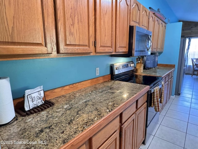 kitchen featuring brown cabinets, light tile patterned floors, tile counters, and stainless steel appliances