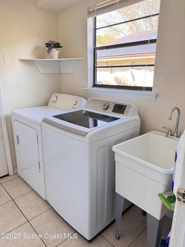 washroom with light tile patterned floors, laundry area, washer and clothes dryer, and a sink