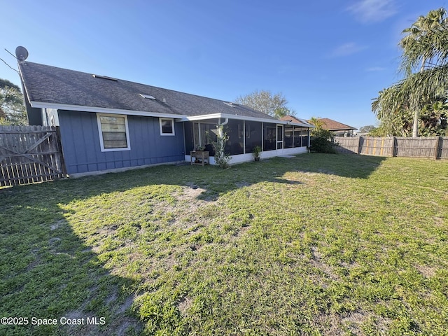 rear view of property featuring a sunroom, a fenced backyard, and a lawn