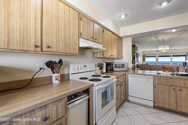 kitchen featuring light tile patterned floors, under cabinet range hood, white appliances, a sink, and an inviting chandelier