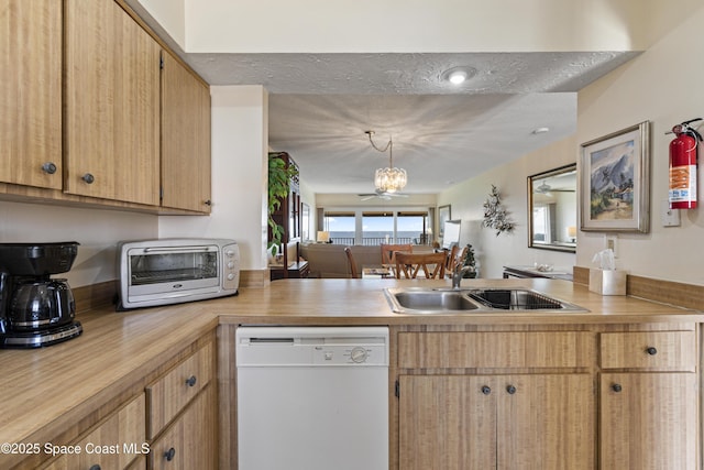 kitchen with a toaster, light countertops, white dishwasher, a sink, and a peninsula