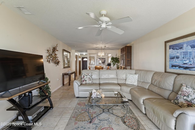 living room featuring visible vents, light tile patterned flooring, a textured ceiling, baseboards, and ceiling fan with notable chandelier