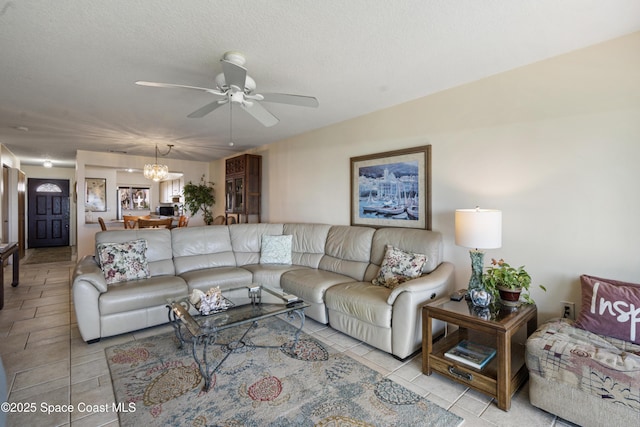 living area featuring light tile patterned flooring, a textured ceiling, and ceiling fan with notable chandelier