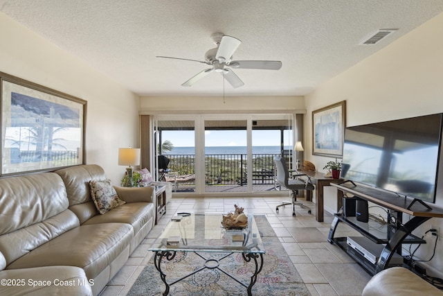 living area with a ceiling fan, visible vents, and a textured ceiling