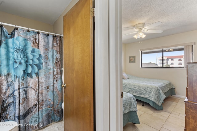 tiled bedroom featuring a ceiling fan, a textured ceiling, and baseboards