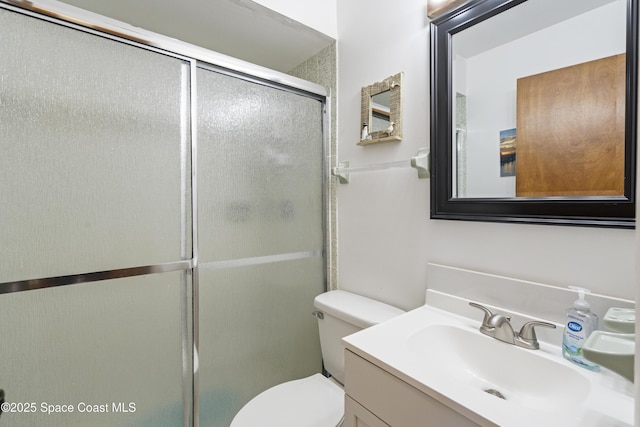 bathroom featuring toilet, a stall shower, and vanity