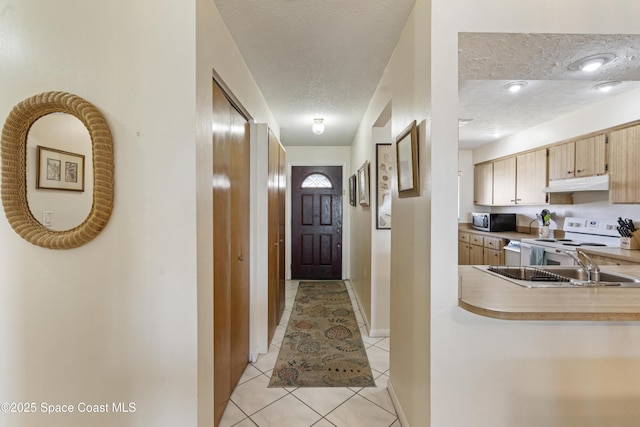 hallway with light tile patterned floors, baseboards, and a textured ceiling