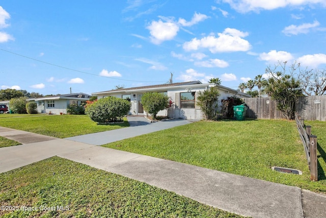 ranch-style home featuring driveway, fence, and a front lawn