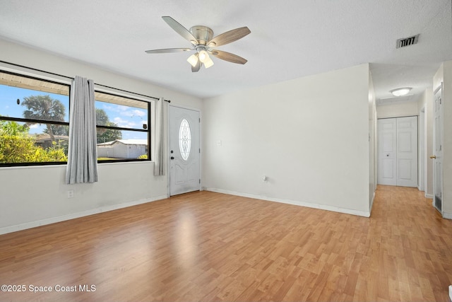 entrance foyer featuring visible vents, light wood-style floors, ceiling fan, a textured ceiling, and baseboards