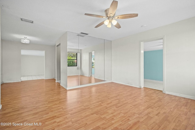 empty room with baseboards, light wood finished floors, visible vents, and a ceiling fan