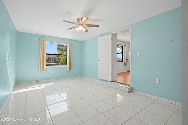 unfurnished room with light tile patterned floors, ceiling fan, and baseboards