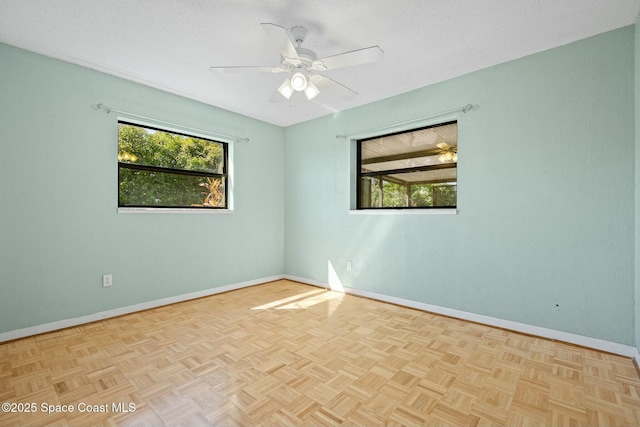 spare room with baseboards, ceiling fan, and a healthy amount of sunlight