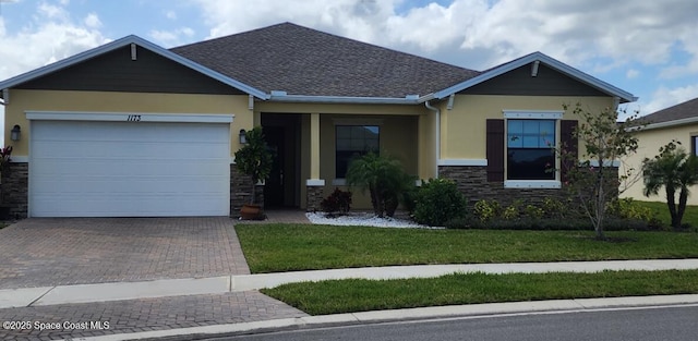 view of front of property with decorative driveway, stone siding, an attached garage, and stucco siding