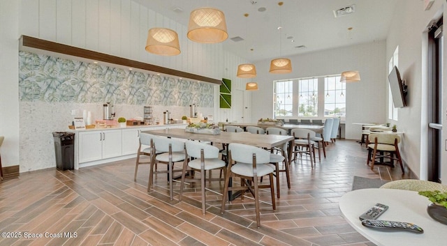 kitchen featuring visible vents, pendant lighting, a high ceiling, white cabinets, and light countertops