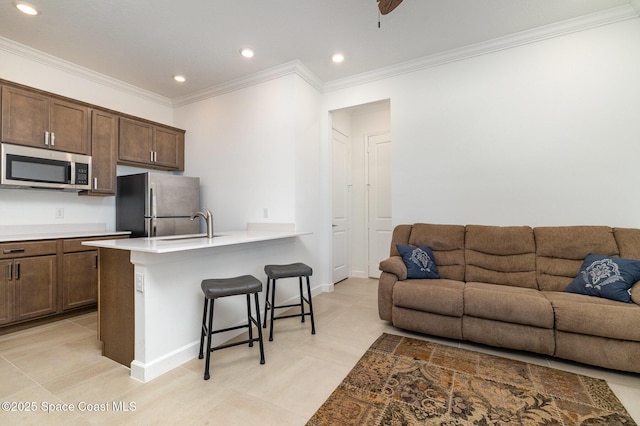 kitchen with crown molding, open floor plan, a breakfast bar, a peninsula, and stainless steel appliances