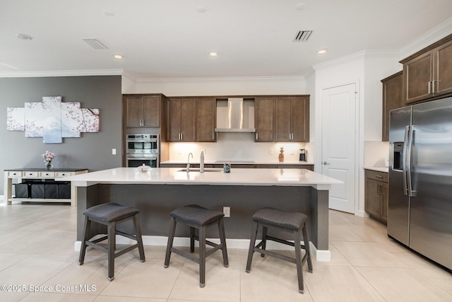 kitchen with a breakfast bar, wall chimney range hood, visible vents, and stainless steel appliances