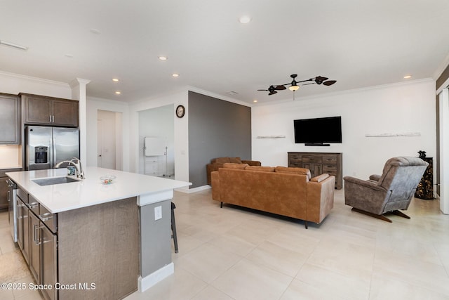 kitchen featuring an island with sink, stainless steel refrigerator with ice dispenser, a sink, dark brown cabinetry, and light countertops